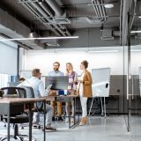 Zwei Kolleginnen und zwei Kollegen unterhalten sich in einem Büro