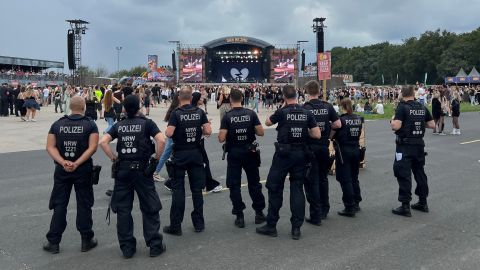 mehrere unifomierte Polizeikräfte beobachten das Treiben, aus dem Hintergrund, vor der Bühne des Festivals