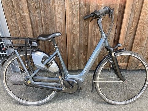 ein Fahrrad mit tiefem Einstieg steht mit dem Lenker angelehnt an einer Holzfassade