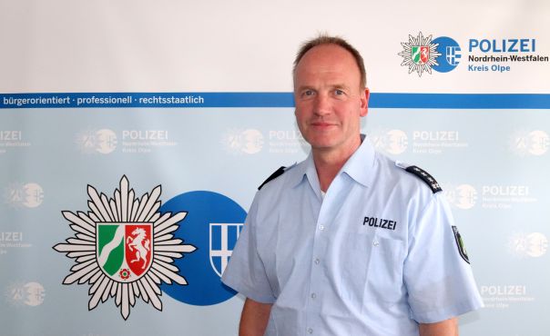 Dirk Rufeger steht in Polizeiuniform vor blauer Wand