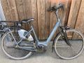 ein Fahrrad mit tiefem Einstieg steht mit dem Lenker angelehnt an einer Holzfassade